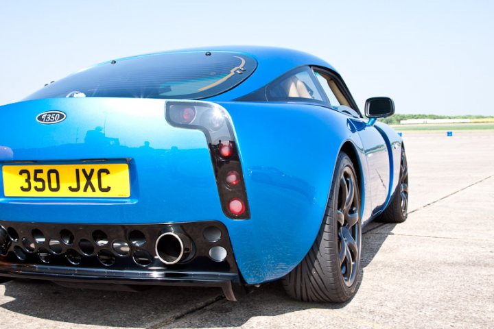 Pistonheads - The image features a striking blue sports car prominently positioned in the center of the frame. This car is a convertible model, characterized by its metal sunroof, and is equipped with a license plate that reads "350 JXC". The car is parked on an airfield, with the vast expanse of the runway extending out behind it. In the background, there is a clear sky, adding to the overall serenity of the scene.