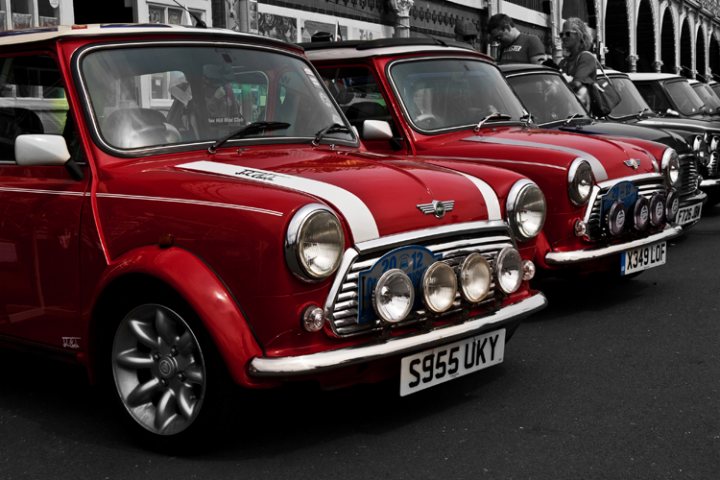 London to Brighton  - Page 1 - Classic Minis - PistonHeads - The image captures a trio of vintage mini cars, parked side by side on a street scene. The first car is a prominent red model with a prominent "UROD" on its license plate, indicating it's registered in the UK. Adjacent to it is a more muted blue car. In the background, there's a third car that shares the same design as the other two, suggesting this might be some sort of car show or gathering. A black and white photo of three vintage planes is also on display, providing a nice contrast to the bright colors of the cars.