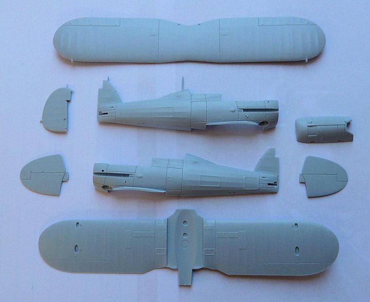 A group of people standing next to each other - Pistonheads - The image shows six plastic pieces representing various parts of an aircraft model. There is a prominent fuselage, a set of wings and a tail section, along with a smaller wing on its side. Additional smaller pieces could be representing the nose or other parts of the aircraft, all laid out on a plain blue surface. The setting suggests a DIY or model-building project. The parts are unpainted and have a greyish-blue color, indicating they are not finished.