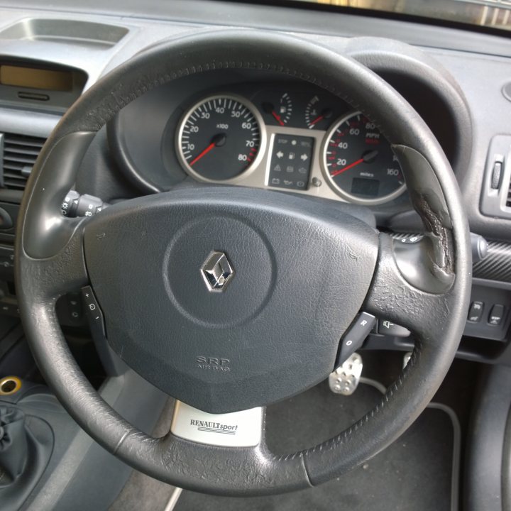 A close up of a motorcycle parked on the ground - Pistonheads - The image shows the interior of a vehicle from the driver's perspective. Dominating the frame is the steering wheel, which includes the Mercedes-Benz logo and multiple buttons and indicators. The speedometer and odometer are partially visible in the background, but the focus is on the steering wheel's center where the brand's insignia is prominently displayed. The steering wheel also has various control buttons and a USB port, indicating modern amenities and comfort in the vehicle. The gray upholstery of the interior gives the inside a well-maintained appearance.