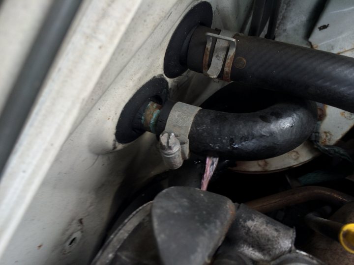 Heater hose No.1 or 2 - Page 1 - Mazda MX5/Eunos/Miata - PistonHeads - This image shows a close-up view of a complex mechanical or industrial setting. The focal point is a weathered metal component, possibly a pipe or tube, with a thick, dark wall that tapers towards the center where there appears to be a connection point. This component is attached to a larger structure, with a portion visible in the background, suggesting it's integrated into a larger system or equipment. The image is taken from a perspective that looks directly into the connection point, creating a somewhat tunnel-like view. There's no text or additional context provided in the image.