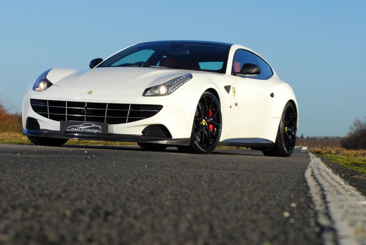 Tragic Ferrari FF.... - Page 1 - Ferrari V12 - PistonHeads - This image showcases a striking white Fiat sports car in motion on a road. The car's sporty design is accentuated by its red-rimmed wheels and sleek black roof. As the car is in motion, it's possible to see the movement and detail in the tarmac. The overall scene suggests a merge of elegance and power, with the vibrant white of the car contrasting against the road and the clear sky above.