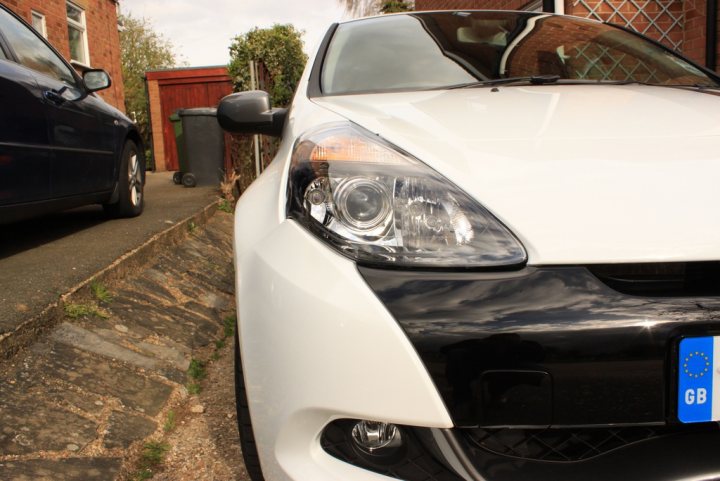 Pistonheads - The image captures a close-up view of the front of a black and white car parked on the side of a street. The car has a distinctive blue and white license plate reading "GB", indicating that it might be registered in the UK. A set of steps is visible in the foreground, leading up to a building on the right side of the image. The scene suggests an urban or suburban setting.