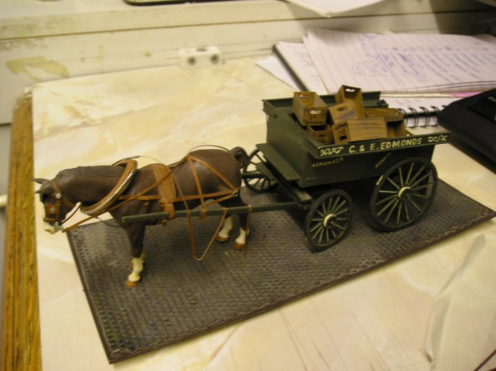 GB Chat thread - Hawker Tempest  - Page 10 - Scale Models - PistonHeads - The image features a miniature figurine of a single horse, which is harnessed to a black carriage-like cart. The horse has a simple design with a strong build indicative of workhorses. It stands on a raised platform that resembles a fiberboard base. The cart is open-sided, with what appears to be a display of wooden blocks, possibly toy horses, in it. This setup gives the impression of a stop-motion animation pose. The backdrop is a plain, light-colored surface that contrasts with the darker tones of the horse and cart.