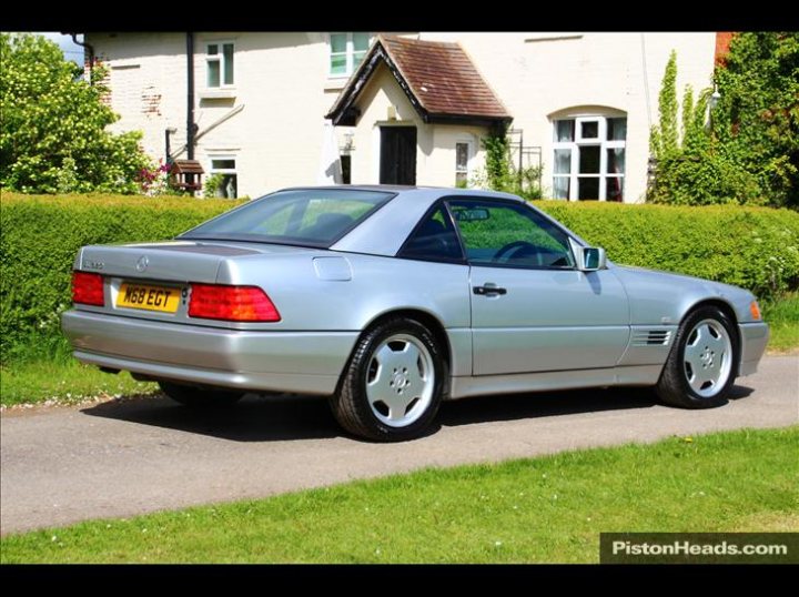 Best 2 Car Combos - Page 3 - General Gassing - PistonHeads - The image depicts a gray, luxury car parked on a driveway. The vehicle appears well-maintained and has a sleek design, suggesting it is a high-end model. The car is facing towards the left side of the image and is positioned in front of a property with a neatly manicured lawn. The scenery includes a small garden at the edge of the image, and a building in the background, possibly a house, given the presence of a staircase. The style of the image seems to be a straightforward, non-artistic photograph, likely intended for a vehicle sales listing or similar purpose.