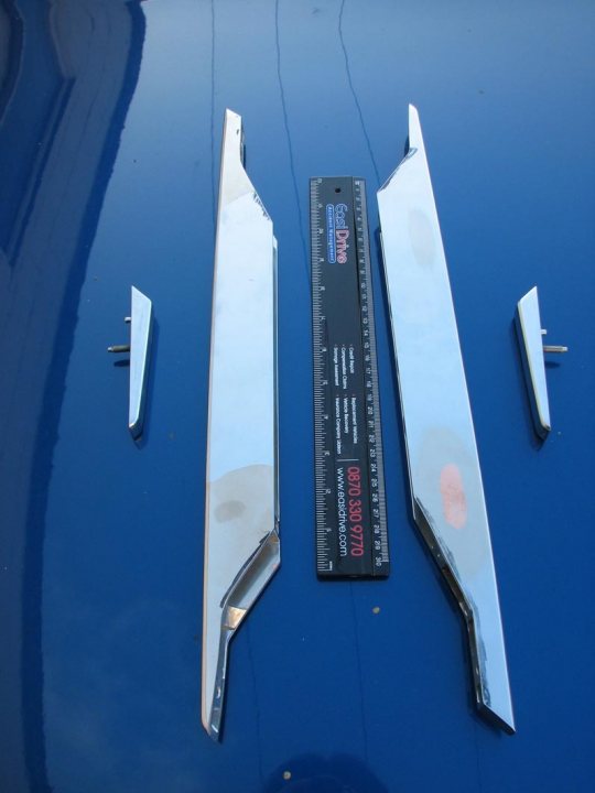 Strakes Side Pistonheads Corrosion - The image showcases a scene of car bodywork, featuring a pair of rear car bumpers with one of them affixed to the hood of a blue car. They are both twisted, suggesting they have been removed from the car possibly for repair or customization. The bumpers, when arranged in a T shape, form a metallic structure that lies over the vehicle, resting on the blue hood. A long single piece resembling a piece of metal tape and a ruler are also part of the arrangement, hinting at the precision and care involved in the process.