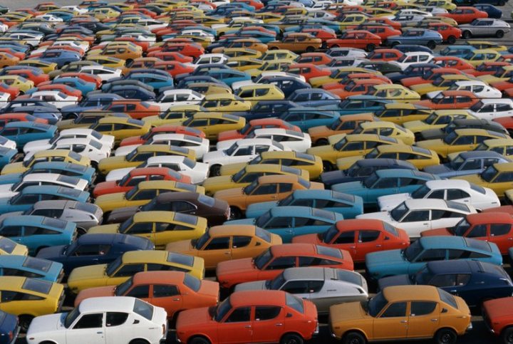 How about a 'period' classics pictures thread - Page 500 - Classic Cars and Yesterday's Heroes - PistonHeads - The image presents an aerial view of a large parking lot. It is filled with numerous cars parked in three separate rows. The cars vary in color, representing a diverse array. The variety in colors creates a vibrant pattern against the common backdrop of the parking lot. Interestingly, the cars seem to be unevenly distributed across the rows, leading to a sense of randomness in the parking arrangement. The view from above provides a comprehensive perspective of the parking layout.