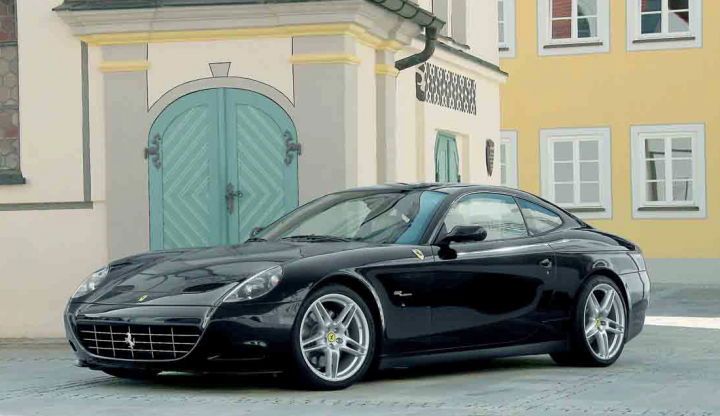 A car is parked next to a parking meter - Pistonheads - The image features a dark-colored sports car parked in front of a compact white building. The car is sleek and appears to be a luxury model, characterized by its aerodynamic design and alloy wheels. The building has a distinct yellow facade and a green door, contrasting with the car's monochrome exterior. There are no visible texts or logos specific to the car or the building in the image, and the background is otherwise nondescript. The car is facing the viewer on a level surface, seemingly ready to drive off.