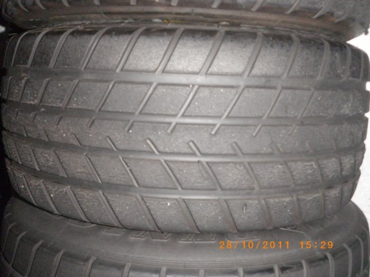 Pistonheads - The image shows a stack of tires, with the deep treads exposed. The tires are square and arranged in a stack that creates an undulating pattern. They exhibit a uniform dark gray color. The date stamp on the image indicates it was taken on October 10, 2011, at 15:29. The focus is on the closest tire, which is partially twisted, showing its inner treads.