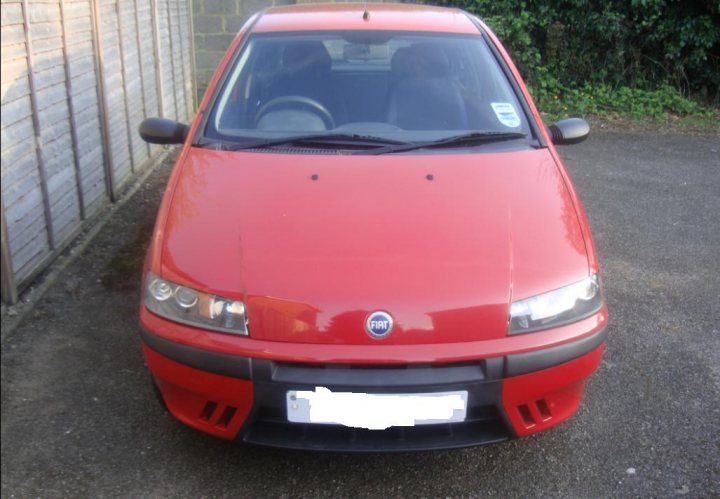 Pistonheads - The image depicts a vibrant, well-lit red car parked on a driveway next to a brick wall. The car appears modern with a visible assembly plant badge on the grill. The front of the car is prominently visible, with headlights turned off, suggesting an outdoor, daytime setting. The overall impression is of a clean, well-maintained vehicle.