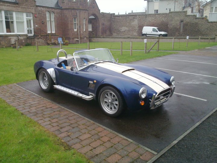 Scotland's Finest Spotted!! [Vol 2] - Page 325 - Scotland - PistonHeads - The image showcases a vintage blue roadster parked in a parking lot adjacent to a brick path. The car is designated for disabled parking by a white stripe on the ground and a brief description in a car-related browsing. An official vehicle is situated close behind the roadster.