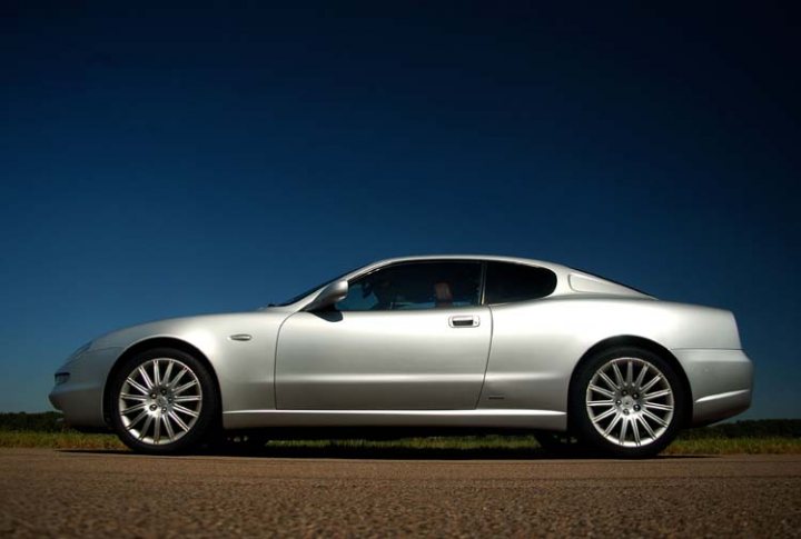 RE: Spotted: Maserati 3200 GT - Page 10 - General Gassing - PistonHeads - The image showcases a sleek and shiny silver sports car, which is both stylish and elegant. The car appears to be a convertible model, with the top down, allowing for a clear view of the interior. The car is parked on a smooth asphalt road, with a secluded rural setting in the background. The street is devoid of any other vehicles or objects, creating a sense of solitude and tranquility.