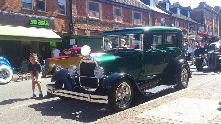 Camberley Town Centre car show - Page 1 - Thames Valley & Surrey - PistonHeads - The image portrays a vintage car show at a street fair. The focal point of the photo is a vibrant green, vintage car. Several spectators are seen observing the old cars on display, contributing to a bustling, celebratory atmosphere. The cars are parked along a brick sidewalk, suggesting a planned event or exhibition. A sign that reads "So Asia" is visible in the distance, possibly indicating the location or a sponsor of the event.