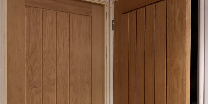 Danish oil on oak veneer doors - Page 1 - Homes, Gardens and DIY - PistonHeads - The image shows a close-up view of a wooden sliding door with vertical slats. The door appears to be made of light-colored wood, possibly oak or similar, and it is partially open. The background is blurred but suggests an interior space, likely a room within a house or building. There are no visible texts or distinguishing marks in the image.