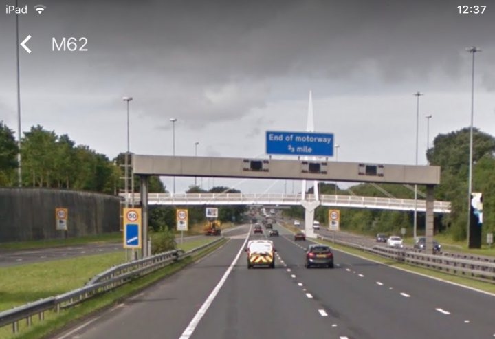 Did I get caught speeding on the m62?  - Page 2 - Speed, Plod & the Law - PistonHeads - The image captures a bustling scene on the M62 motorway in the UK. The highway is densely packed with multiple lanes filled with vehicles. Construction activities are taking place, as evidenced by warning signs like the one with the number 16. On the left side of the image, there's a bus stop with a bench where commuters can wait for their ride. At the very end of the motorway, there's a sign indicating "End of Motorway, 1 mile".