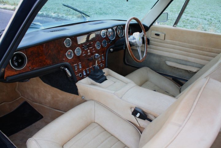 Tell me about the Elan +2 - Page 1 - General Lotus Stuff - PistonHeads - The image shows the interior of a vintage car with a pale blue or creme interior. The car appears to be from the late 1950s, judging by the design of the dashboard and the style of the upholstery. The driver's side has a black rectangle around the speedometer and other gauges, providing a dark contrast to the beige interior. The car's wood grain panels add to its classic look. A notable feature is the lack of modern amenities, suggesting the car is not currently in service.