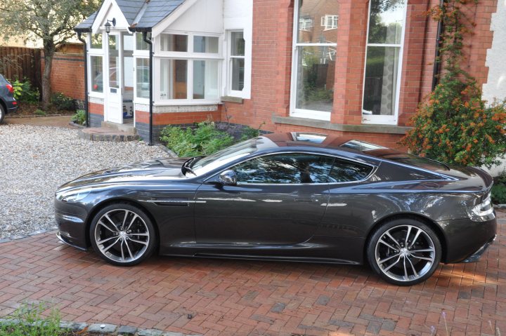 Vantage Finally Dbs Pistonheads - The image features a sleek, sports car parked on a brick driveway of a two-story house, with the vehicle's glossy finish reflecting the architectural elements of the structure. The car's design and placement suggest a well-kept and potentially luxurious home. The plate number on the car is clearly visible. The brickwork of the house and driveway provide a warm contrast to the shiny exterior of the vehicle, hinting at a harmonious blend of modern and traditional elements in the property's design.