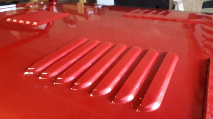 How much vinyl to wrap a Caterham? - Page 1 - Caterham - PistonHeads UK - The image shows a large, red metallic surface with several ridges or bumps. It appears to be a piece of machinery or equipment due to its structure and the way it reflects light. This could potentially be an industrial object like part of a conveyor system or machinery of some sort. The background is not clearly visible but seems to be indoors, perhaps in a workshop or factory setting. There are no texts or distinguishable marks that indicate any specific use or manufacturer.