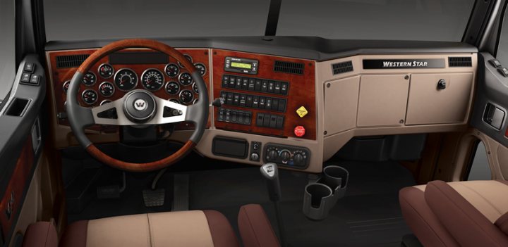 Artic Tractor Axle configurations  - Page 1 - Commercial Break - PistonHeads - This image captures the interior of a luxurious car, focusing on the driver's side. The side panel is in shades of wood, complementing the black and white steering wheel. A central panel runs through the dashboard, housing an array of buttons, dials, and screens, indicative of advanced technology. Cup holders are neatly placed on the side, ready for the driver's beverages. A distinctive feature of this vehicle is the unique Western Star insignia on the dashboard.