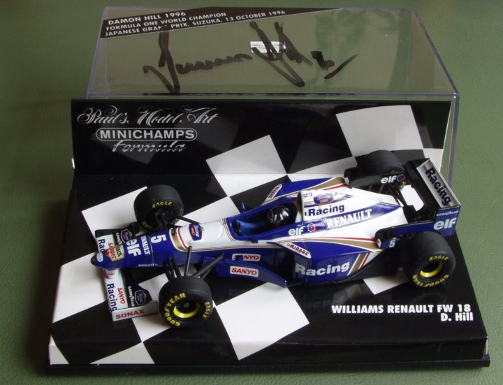 Pistonheads Collection - The image showcases a miniature Williams Renault FW18 Formula 1 car, part of the Minichamps Infinite Future Collection. The car appears in a box with a checkerboard pattern, possibly indicating a historical or nostalgic theme. At the top of the box, there is an inscription in what seems to be a signature or autograph. The year "1996" is prominently displayed, suggesting that the car might represent the 1996 Formula 1 season or a specific model from that period. The words "Damon Hill" and "Williams" are visible too, indicating that this is a tribute model to Damon Hill, a famous Formula 1 driver and a former driver for the Williams team.