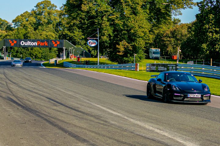 RE: Oulton Park Saturday Service | 21st September - Page 5 - General Gassing - PistonHeads - The image is a photograph capturing a scene on a race track. A black sports car with an open top, possibly for aerodynamic purposes or to allow the driver to feel more connected to their surroundings, is in motion. The vehicle appears to be at the tail end of a racing session, as indicated by the dirt kicked up behind it and its position towards the left edge of the track.

The race track itself has a paved surface and is lined with grassy areas. There are no other cars visible on the track, suggesting that this particular moment captures solitude or an earlier lap of racing.

In the background, there's a signpost reading "Croydon," indicating the location might be in the United Kingdom, specifically near a place called Croydon. The surrounding area appears to be a rural landscape with trees and greenery, providing a natural backdrop to the track. There are no people visible in the image, emphasizing the sense of speed and isolation that often accompanies racing events.