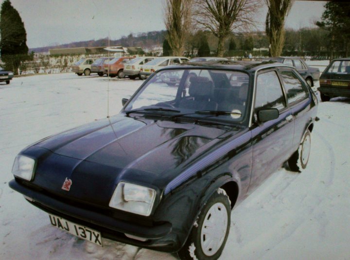 Classics left to die/rotting pics - Vol 2 - Page 339 - Classic Cars and Yesterday's Heroes - PistonHeads UK - The image shows a vintage car parked in a snowy outdoor area. The vehicle is black with white trim and appears to be a hatchback, possibly from the 1980s or 1990s judging by its design. There are no visible people or other objects around the car. The setting seems cold, indicated by the presence of snow on the ground. In the background, there is another car and some buildings, suggesting an urban or suburban environment. The style of the photo is candid and informative, aiming to capture the vehicle in its current state rather than for artistic purposes.