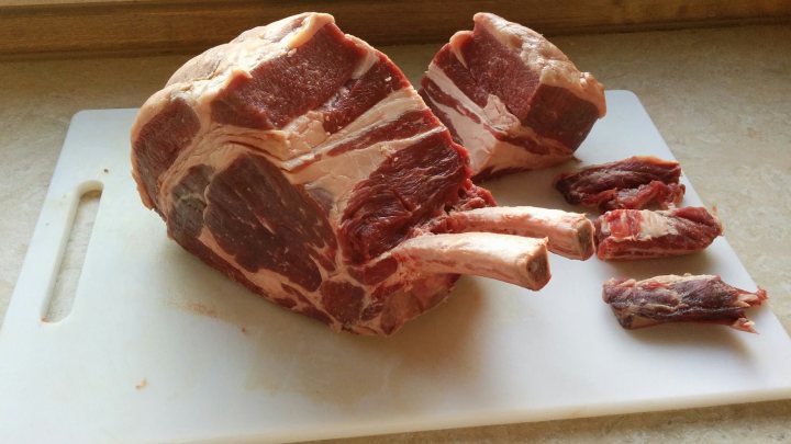 Photo of your dinner (vol 2) - Page 246 - Food, Drink & Restaurants - PistonHeads - The image shows a large piece of fresh meat, specifically pork, cut into chops and placed on a cutting board. There are some of the chops separated, revealing the fat and marbling within the meat. The cutting board is placed on a countertop, and there are a few smaller pieces of meat lying on it, which appear to have been detached from the main cut. The pork has a rich, meaty color.