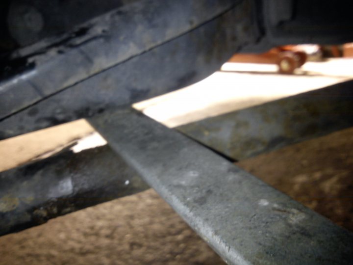 A close up of a bench on a city street - Pistonheads - This photo shows a close-up of a car component, specifically the underside of a body panel or part of the suspension. There's metal frame and some components that appear to be parts of the suspension system or the interior of the vehicle, such as the floor lining. The car is likely dark grey in color, as the visibility is somewhat dim and the surface appears to be dirty, which suggests it might be an underbody shot or taken in a poorly lit area. The bottom corners of the image are blurry due to the close-up angle and lighting conditions, which detracts from the overall clarity of the photo.