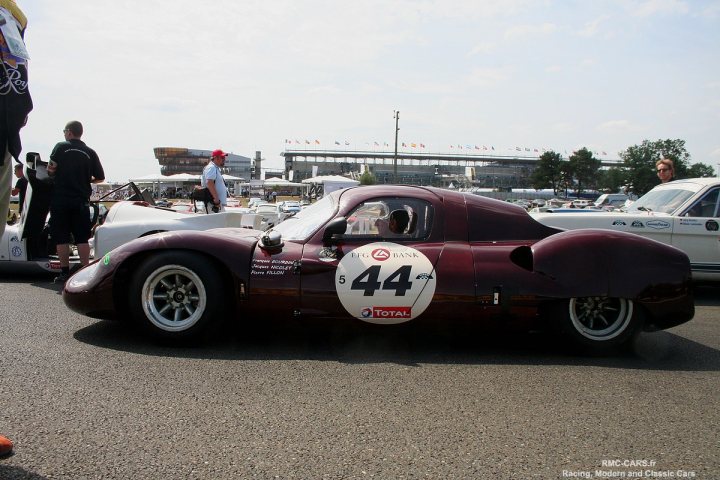 GRP monocoque based on steel car? - Page 2 - Kit Cars - PistonHeads - The image showcases a vintage race car on a racetrack. The car is prominently featured in the foreground, with white walls and the number 44 displayed on its side. It's parked in a paddock environment where several other cars and people can also be seen. The perspective suggests the viewer is standing near the car, possibly getting ready for a race or event. The scene conveys a sense of anticipation and excitement associated with classic motorsports.