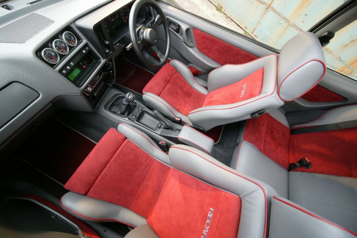 Pistonheads - The car's interior is predominantly red and white, with two front seats featuring a mix of seat cover materials. The vehicle features a multi-gauge dashboard with a radio interface. It has two front doors, each door equipped with adequate window power controls and door locks. The driver's seat is positioned with the steering wheel placed on the right side of the steering column. The car's floor mat is red, matching with the seat covers.