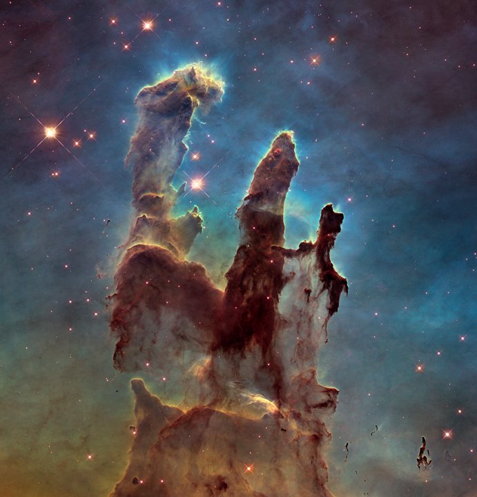 Pillars of Creation redux. - Page 1 - Science! - PistonHeads - The image displays a breathtaking view of a galaxy, likely the Eiffel Nebula, painted with vibrant colors against a dark blue sky speckled with numerous distant stars. The galaxy is rich in colors - predominantly shades of green, hints of blue and orange, and is dotted with startling patches of white, resembling a steamer or an architecture masterpiece. Cosmic tendrils, looking like the silhouette of electrified waterfalls, extend across the image, giving it an ethereal and majestic aspect. This image seems to have been taken with the Hubble Space Telescope, the instrument known for its stunning high-definition images of the cosmos.