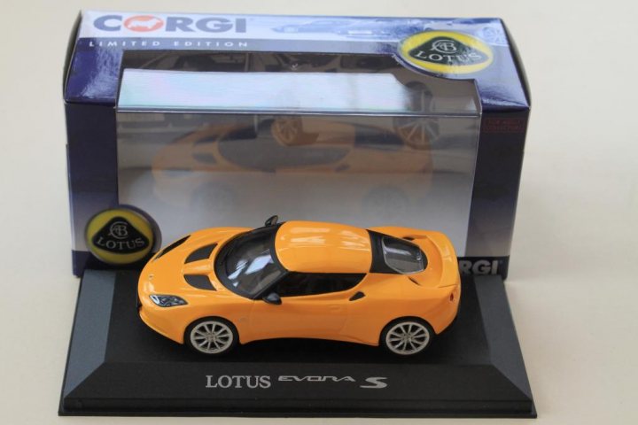 A red suitcase sitting on top of a car - Pistonheads - The image showcases a vibrant lotus evora S automotive toy model. This toy car is meticulously crafted with orange and yellow hues, resembling an actual sports car. The car is displayed in its transparent plastic packaging, strongly labeled with the brand name "lotus". The perspective of the image is from a rear side view, allowing one to appreciate the detailed interior and the finesse of the design. The package rests on a black stand, positioned against a neutral white background that emphasizes the toy model.