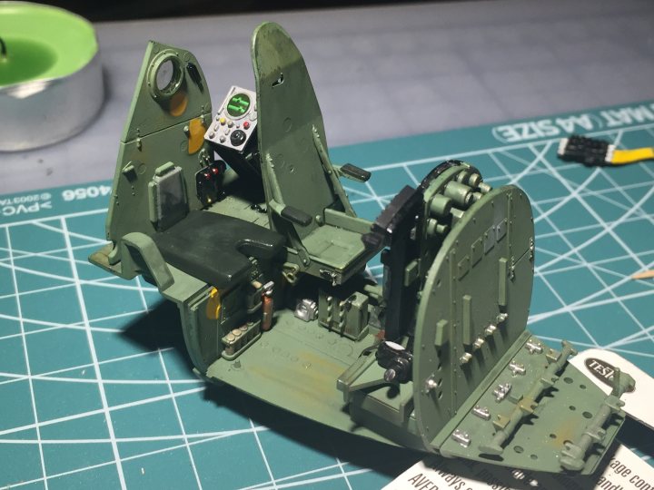 Tamiya 1/32nd Mosquito FBIV - build! - Page 1 - Scale Models - PistonHeads - The image displays a detailed, small-scale model of a fighter jet cockpit. The model is painted to resemble the interior of a military aircraft, featuring green coloring. It includes multiple controls and displays, such as a flight stick, throttle, and various instruments. Additionally, there is an open Panel Puppet, presumably for manipulation or posing, and an electronic board, likely a part of the model's functionality or interaction. The action figure itself appears well-crafted with intricate details, suggesting it might be a collectible or a toy for enthusiasts.