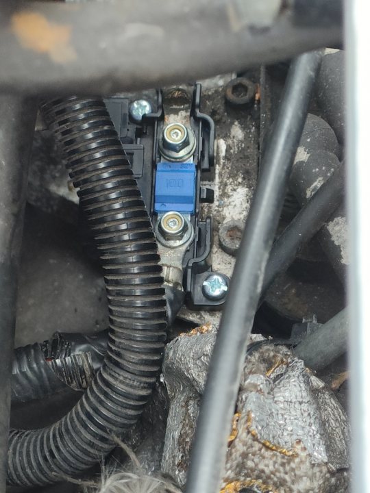 Pistonheads - The image shows a close-up view of the underside of a vehicle, focusing on the mechanical components. A hose is visible with a blue electrical connector attached to it, possibly for an air pump or similar system. There are several wires and connectors in various colors, suggesting they may be from different electronic systems. Additionally, there's a wire bundle that appears to be connected to some form of motor or solenoid. The background is mostly obscured by the car's structure, but it gives a sense of the vehicle's interior.