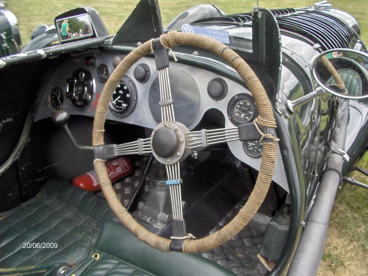 Rally Raleigh Pistonheads - The image showcases a vintage race car, steeped in history and craftsmanship. The focus is on its interior, specifically the driver's seat. This seat is adorned with a matching green leather upholstery, with a large steering wheel featuring at its center a metal inlay and flanked on the sides with black plastic knobs. The car exudes an air of nostalgia, reminiscent of a bygone era of speed and competition.