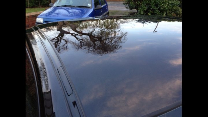 A car with a surfboard strapped to the back - Pistonheads - The image showcases a blue car parked in front of a hedge. The shiny surface of the car reflects the peaceful park scene around it, indicating a calm, sunny day. The hedge provides a natural barrier between the car and the park, adding to the serene setting. The perspective of the photo, taken from behind another car parked next to the blue one, captures both the vehicle and its surroundings in a harmonious composition.