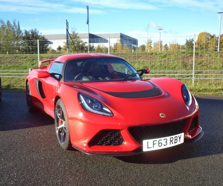 A red and black motorcycle parked in a field - Pistonheads - The image shows a red sports car parked on a road during the day. The car has a sleek design with a large front grille and angular headlights, indicative of sports car design. The vehicle is parked next to a fence and facing towards the right side of the image, with a clear sky, lush green trees, and foliage in the background. The license plate of the car is visible and reads "LF63 RBY." The car's design features aerodynamic curves, a streamlined hood, and a wide stance over the rear wheels, hinting at its potential for high-speed performance.