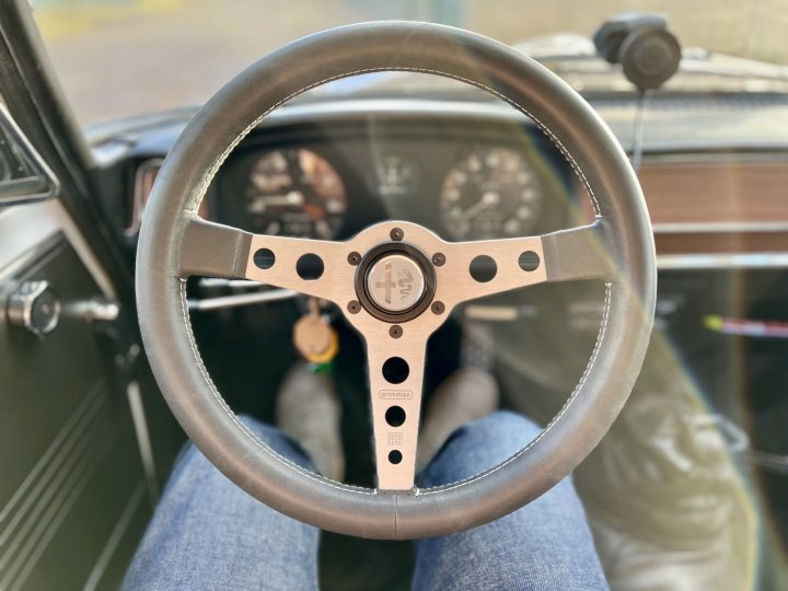 1970 Alfa Romeo Giulia 1300 TI - Page 15 - Readers' Cars - PistonHeads UK - The image captures a close-up view of the driver's side wheel of an antique car. The steering wheel is made of wood with brass fittings and has a distinct vintage design. It appears to be in the center console of the vehicle, suggesting that the car is likely of British origin given the style of the steering wheel.