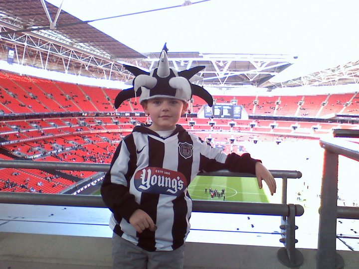 league two 2009 2010 - Page 1 - Sports - PistonHeads - In the heart of a bustling sports stadium, a young boy stands out, embodying the spirit of the event. He is dressed in a striking costume that features a large gray elephant hat adorned with red stars, capturing the attention of those around him. His attire is further enhanced with a black and white striped shirt, donning the word "YOUNG'S" prominently in white, hinting at a playful and enthusiastic approach to the game. His gray pants completes his outfit, leaving him poised on the sidelines, ready to cheer on his favorite team. The stadium itself is alive with color and activity, with rows upon rows of red seats stretching out behind him, soon to be filled with eager fans. This image captures the essence of sporting events, where individuals come together to share in the collective excitement and passion.