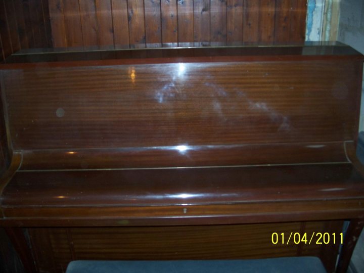 Buying Pistonheads Worth Piano - The image showcases a vintage wooden piano with a stained finish, located inside a room. A glass case encloses the piano, which is positioned against a wall. A date stamp of "01/04/2011" is prominently displayed on the glass, indicating the image or event was captured on that day. The strap on the nearest bench also adds to the antique charm of the scene.