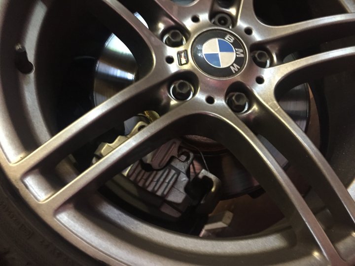 e90 M-Sport brakes - Page 1 - BMW General - PistonHeads - The image shows a close-up of a car wheel. The wheel is gold-colored with a multi-spoke design. At the center of the wheel, the BMW logo is prominently displayed. Inside the wheel, you can see a mechanism that is part of the brake system. The edges of the image lead into the spokes of the wheel.