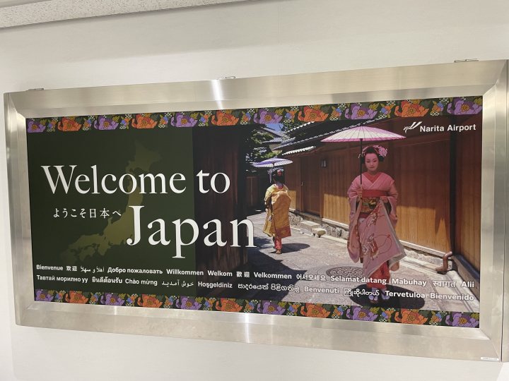 Pistonheads - The image shows a sign welcoming visitors to Japan. It's written in Japanese characters, with the English word "Welcome" prominently displayed at the top. The backdrop is a photograph of a scene from Japan, featuring what appears to be traditional Japanese attire and architecture.