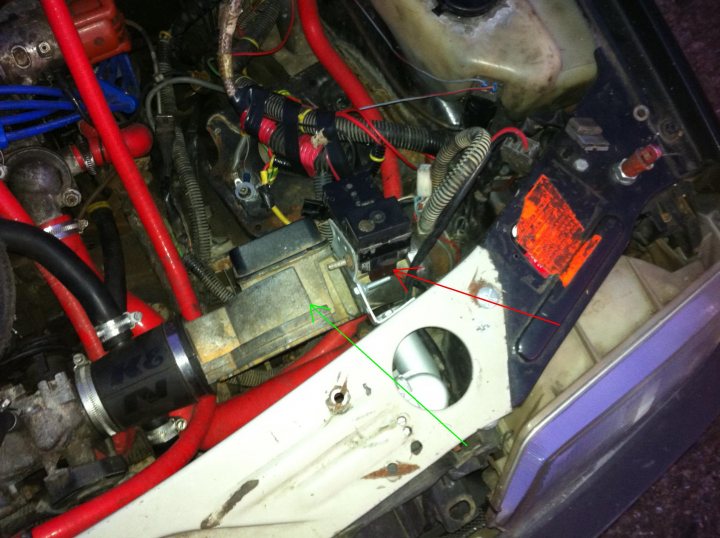 205 track slag, help identifying a couple of bits - Page 1 - French Bred - PistonHeads - The image shows the interior of a vehicle's engine compartment. In the foreground, there are multiple wires with red and black connectors, along with an electrical connection with a metallic clamp. The engine appears to be disassembled, with visible bolts and connections. In the background, the engine's belt and pulley components are partially visible, indicating that some of the mechanical workings are exposed.