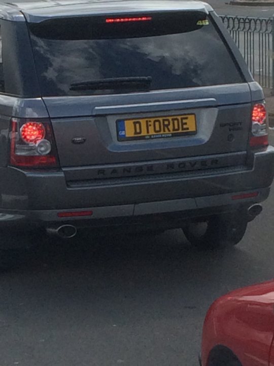 What C124PPY personalised plates have you seen recently? - Page 479 - General Gassing - PistonHeads - The image shows a silver SUV driving on a road, with a visible license plate. There are also red brake lights at the back of the vehicle. In the background, there is a white fence and a building. Additionally, there is a person visible in the background, though they are not the main focus of the image. The overall scene suggests an urban environment.