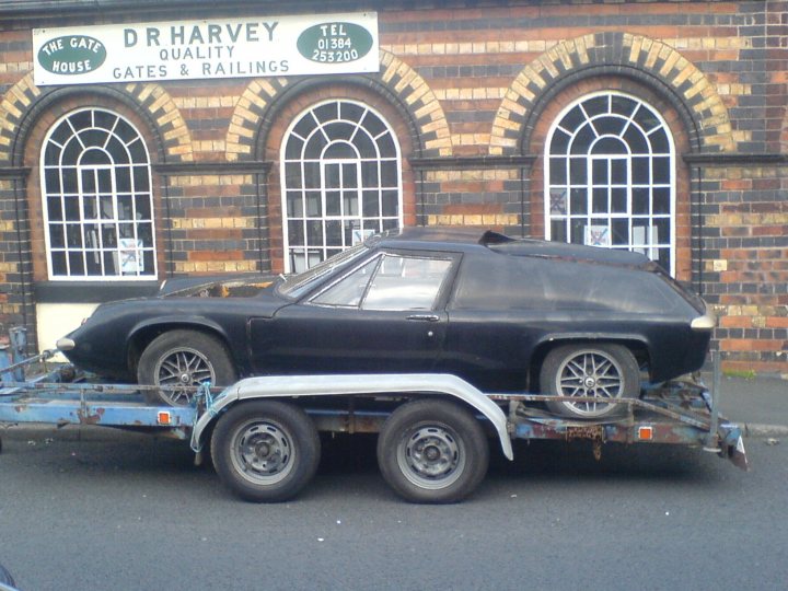 Europa Jps Pistonheads - This image shows a vintage black car being towed by a white and blue car carrier trailer. The car being towed appears to be a classic or sports model, with a distinct shape and a small window in the center of its hood. The trailer is used for automobile transport and has high sides and is parked on what seems to be a city street.

In the background, there is a red brick building with arched windows. Above the building, there's a sign that reads "Dr Harvey Quality Gates & Railings." The style of the car and the details of the building and the sign suggest that the image might be taken in an urban area with historical architectural features.