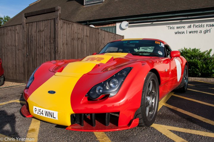 Pistonheads - The image captures a vibrant scene featuring a very unique sports car that's painted in a striking combination of red and yellow. This car stands out because of its bold colors, which mirror those of the Netherlands' national soccer team, adding a sense of national pride to the scene. The car is parked in a lot of a building, indicating that it might be stationed there temporarily. In the background, nature is making its presence felt with trees, suggesting the location is in a city park or a similar green space.