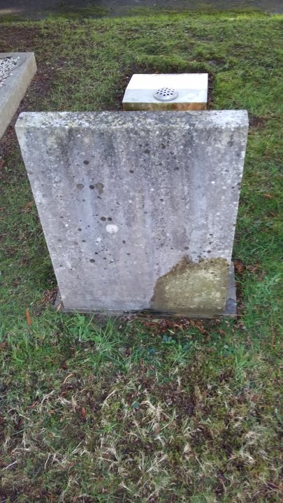 Headstone cleaning - Page 1 - The Lounge - PistonHeads - The image shows a section of an outdoor space with a focus on a stone monument or plaque. The stone is square and appears to be made of concrete or cement. There's a small amount of moisture, possibly from rain, on the surface of the stone, indicating recent precipitation. The surrounding area includes grass, suggesting a park or garden setting. To the right of the image, there are two images of a cemetery headstone and what appears to be a photograph of a grave marker, both in color. The style of the image is a composite with multiple layers, combining different subjects into a single frame.