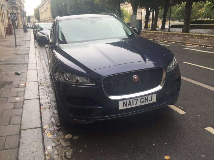 Our other cars - Page 10 - Aston Martin - PistonHeads - The image shows a dark blue Jaguar car parked on a city street. The car is positioned near the curb and is facing the left side of the frame. There's a license plate visible at the front of the vehicle with the registration number "N17 GHJ." The surroundings include multiple parked cars along the street, indicating a residential or commercial area with buildings that are slightly blurred in the background.