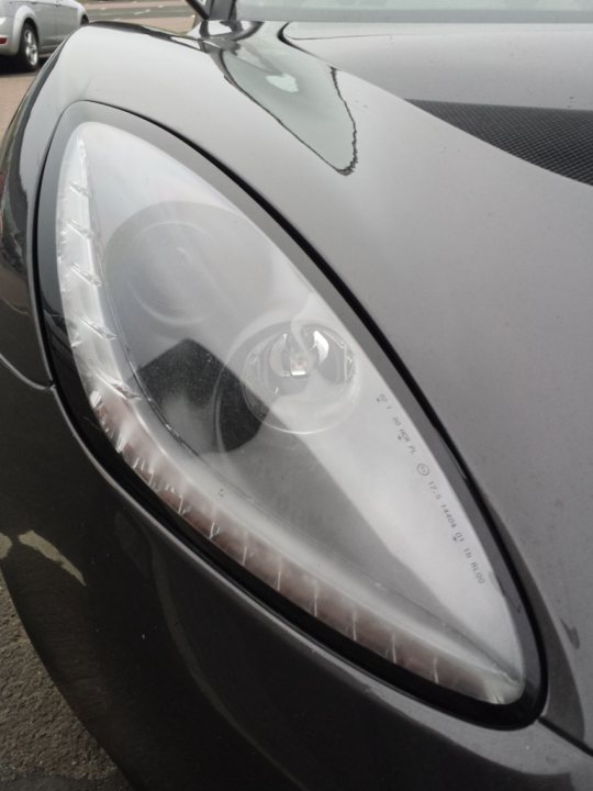 A close up of a car parked on a street - Pistonheads - The image showcases the front of a car, specifically focusing on the headlight. The headlight is off, but it appears to have a silver or reflective layer in its center, adding to its modern and sleek design. It's a close-up view that emphasizes the headlight's shape and detail. Behind the car, there are other vehicles visible, indicating that this photo was taken in a car park or similar setting. The overall image suggests a setting focused on cars and their designs.