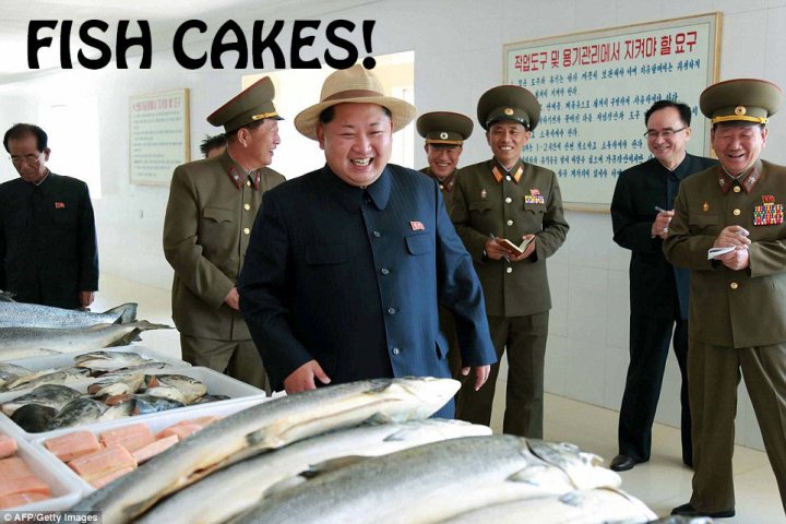 North Korea photoshop contest - Page 29 - The Lounge - PistonHeads - The image portrays a humorous scene set in a fish store. The central figure is a man, possibly of military facial features due to his style of hair and mustache, who is smiling brightly at the camera. He is standing in front of fresh fish and seafood, which takes up a significant part of the image. Surrounding him are several men, likely of Asian descent, also smiling broadly, indicating a jovial atmosphere. The men are dressed in formal military suits complete with hats, adorned with decorative badges and medals. Above them hangs a sign in a foreign script, adding to the foreign setting of the store. The large text "FISH CAKES!" at the top of the image, set in a bold, cartoonish font, completes the humorous tone of the image, suggesting a playful blending of themes related to fish and military personnel.